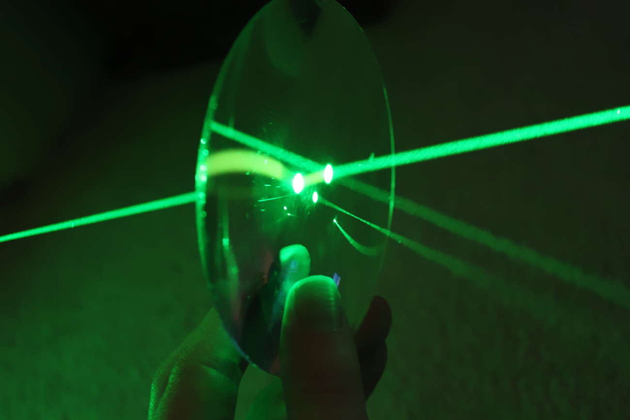 Un faisceau laser vert sur une lentille de verre.